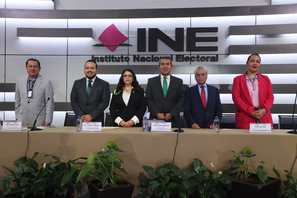 Jorge Montaño acompañado de cuatro personas ty la Secretaria Ejecutiva del INE en el podium principal