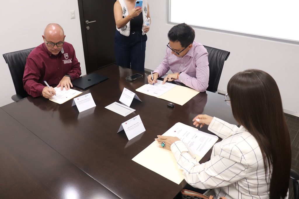 dos hombres y una mujer sentados firmando unos documentos