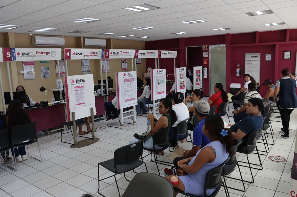 personas sentadas al interior de un módulo del INE esperando ser atendidas