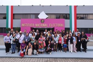 Personas participantes e invitados parados frente al edificio A posando para la foto.