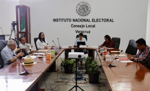 Varias personas sentadas alrededor de una mesa con micrófonos negros delgados