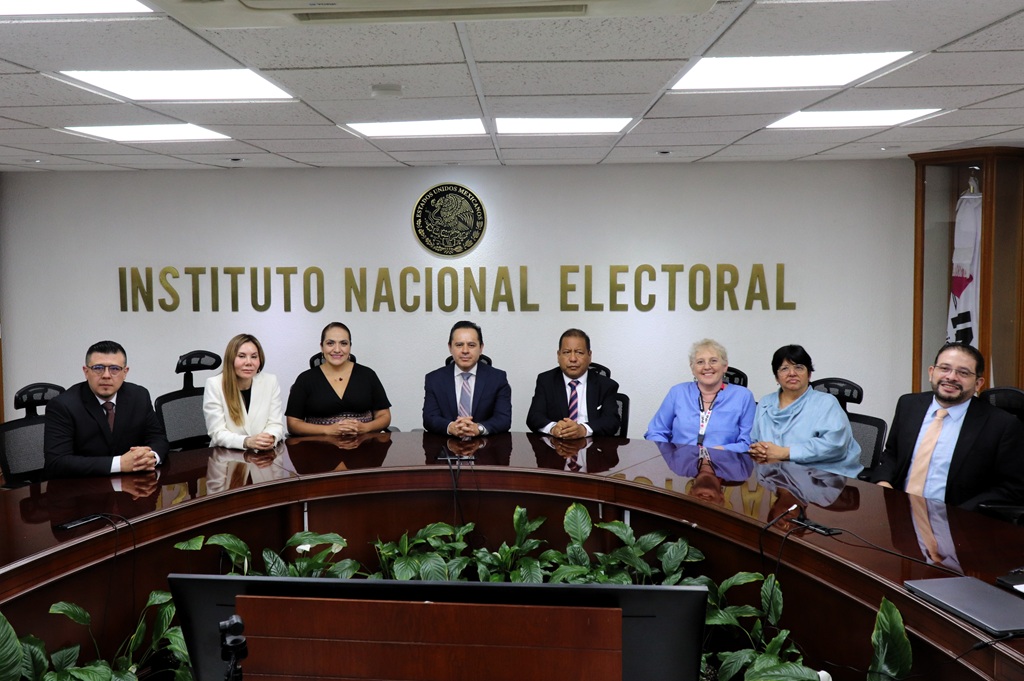 Ocho personas sentadas en un salón, posando para la fotografía