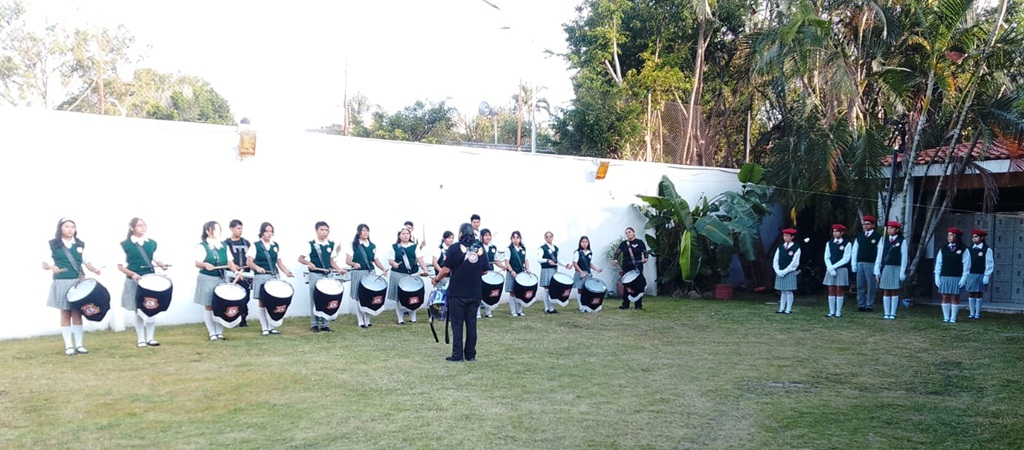 personas uniformadas en línea horizontal tocando tambores