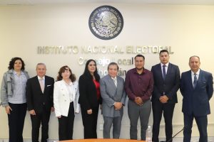 ocho personas de pie abajo del escudo nacional y letras doradas