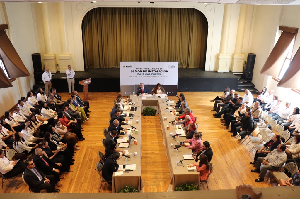 personas en un teatro sentadas algunas frente a una mesa y otras en sillas a los extremos del lugar