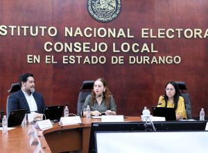 dos mujeres y un hombre sentados en una sala de juntas