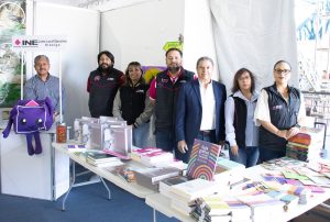 Siete personas de pie frente a mesas con libros