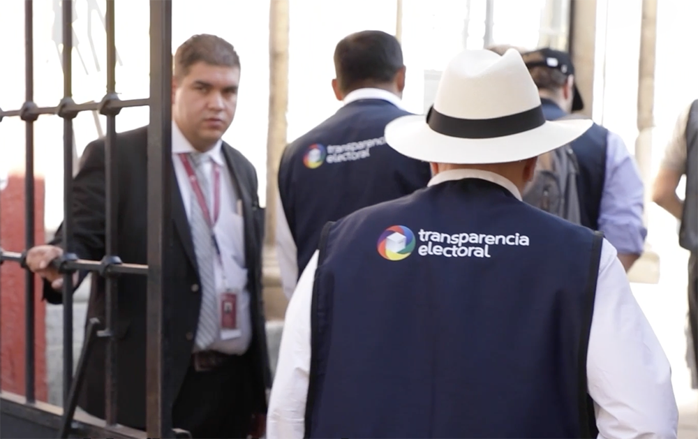 persona de espaldas con un chaleco que dice Trasparencia electoral