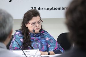 Mujer sentada con lentes frente a un micrófono