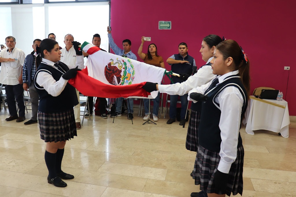 cinco estudiantes uniformadas extendiendo la bandera nacional
