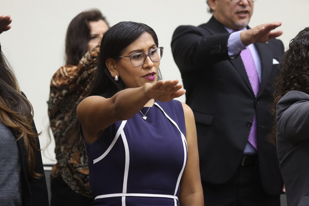 mujer de pie, vestido morado con el brazo derecho extendido al frente