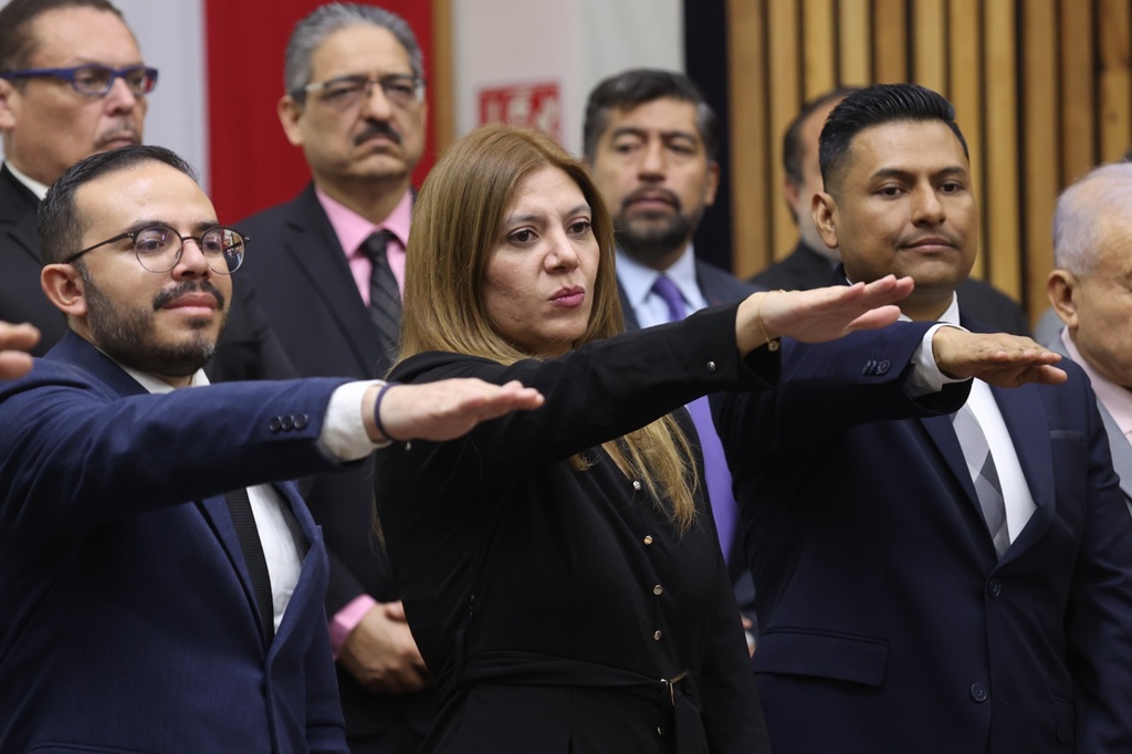 mujer de pie vestida de negro con el brazo derecho extendido al frente