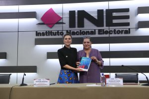 Guadalupe Taddei Consejera Presidenta del INE y Eleonora Betancur González, Representante de ONU Mujeres en México paradas en el estrado con la publicación en las manos.