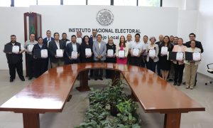 veintitrés personas de pie sosteniendo diplomas