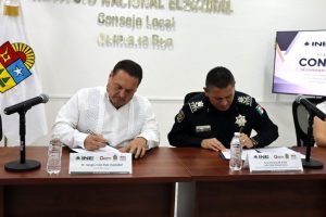 dos hombres sentados, firmando documentos