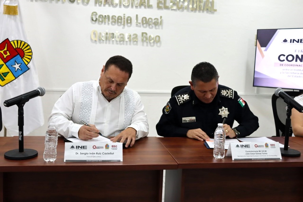 dos hombres sentados, firmando documentos