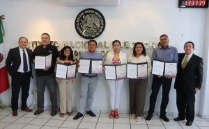 ocho personas de pie posando con diplomas