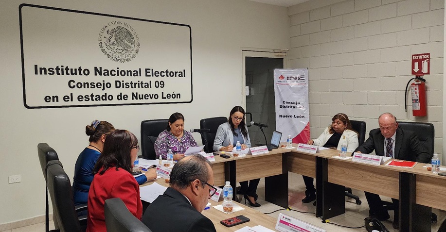 siete personas en un salón blanco sentadas al rededor de una mesa