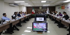 personas sentadas en una sala de juntas votando a mano alzada