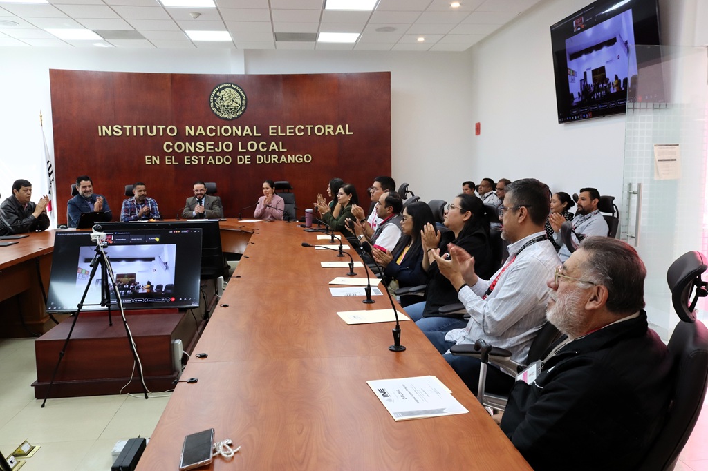 más de diez personas sentadas alrededor de una mesa ovalada aplaudiendo