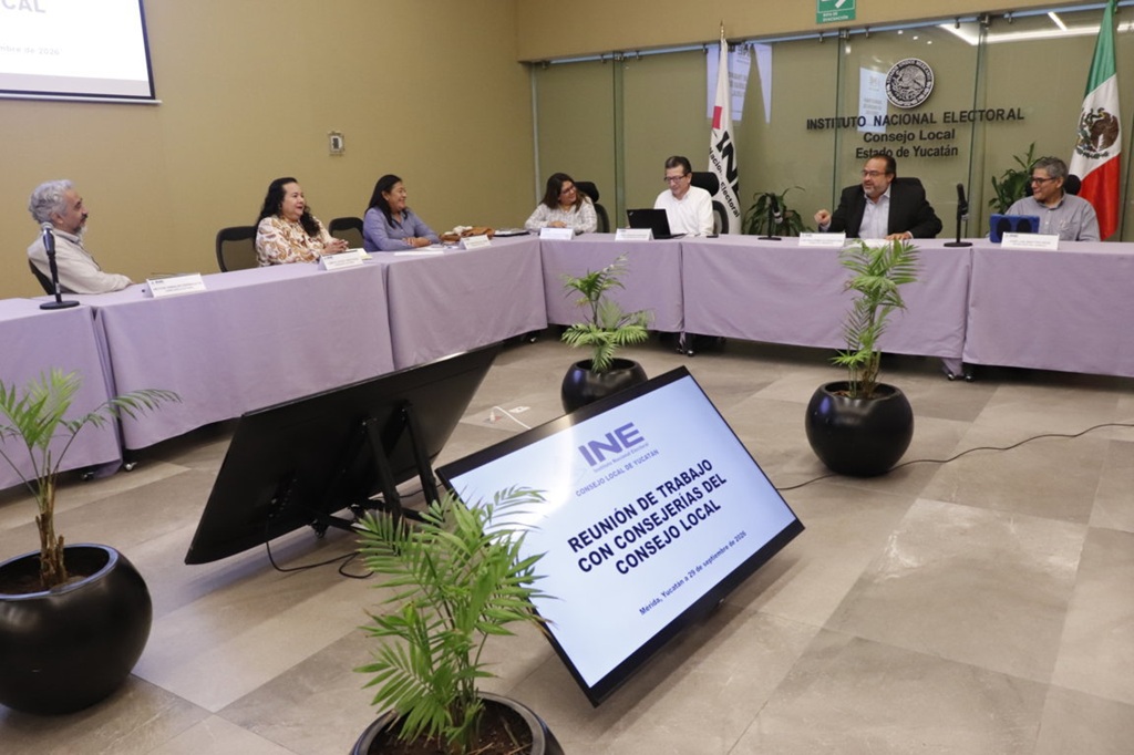 Varias personas sentadas alrededor de una mesa con mantel morado