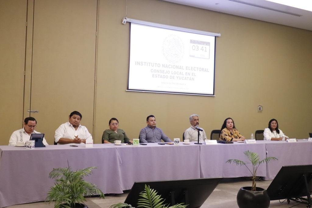 siete personas sentadas frente a una mesa con mantel morado