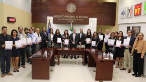 veintidós personas de pie sosteniendo diplomas