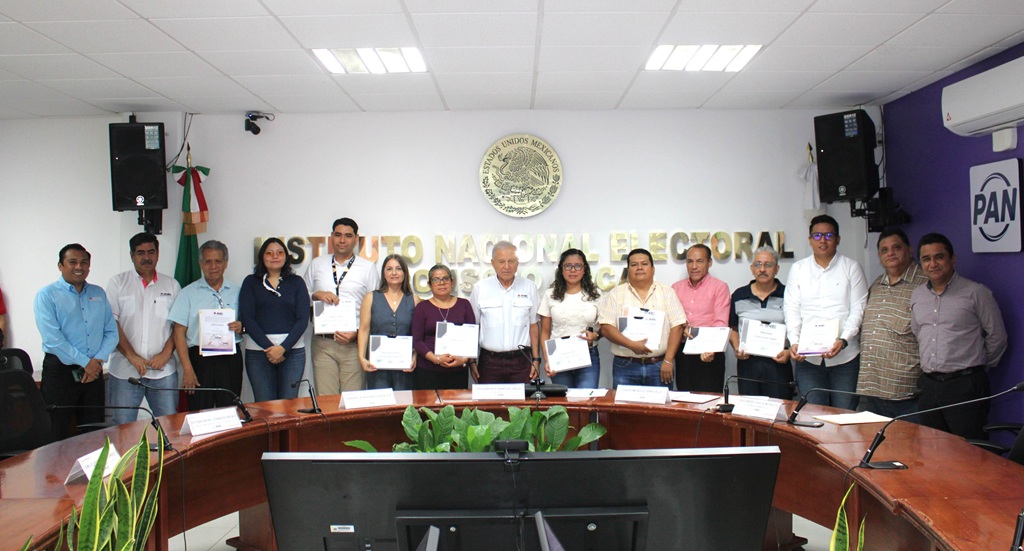quince personas de pie. Cada persona sostiene un diploma