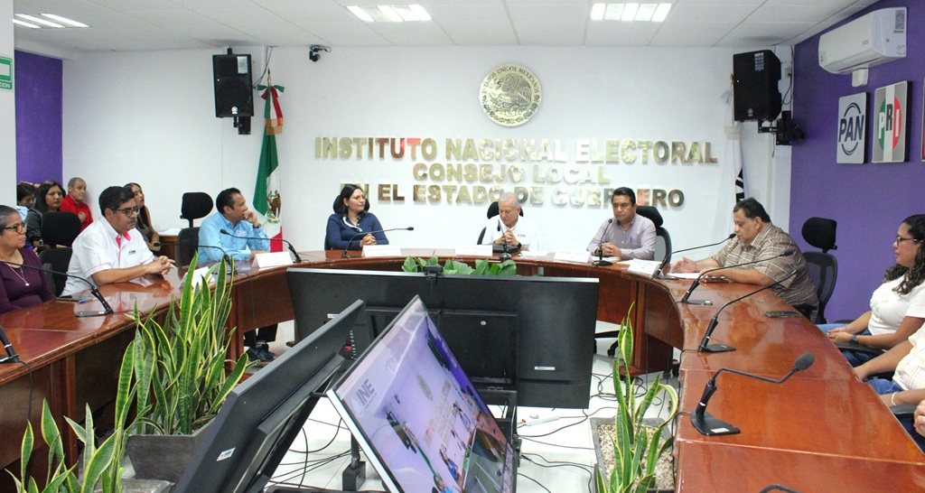 personas sentadas alrededor de una mesa de madera con micrófonos
