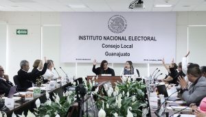 varias personas sentadas alrededor de una mesa votando a mano alzada