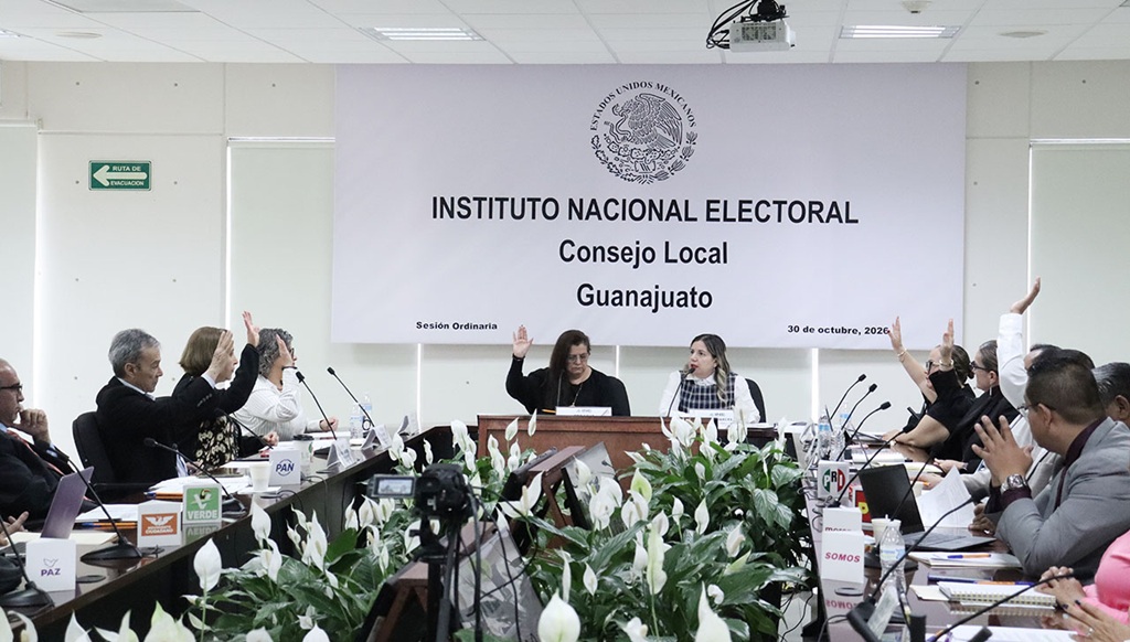 varias personas sentadas alrededor de una mesa votando a mano alzada