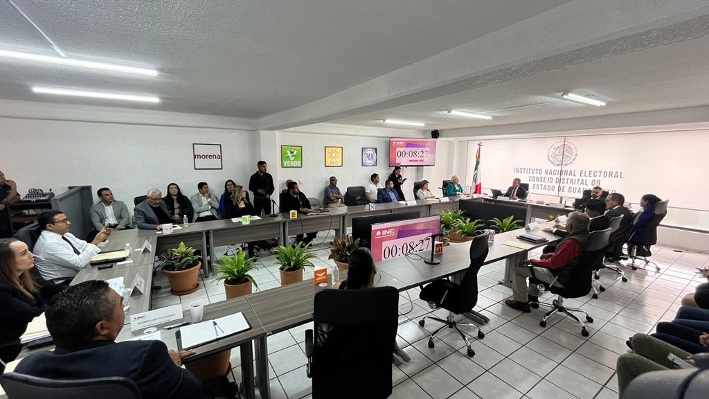 más de diez personas sentadas adentro de un salón blanco