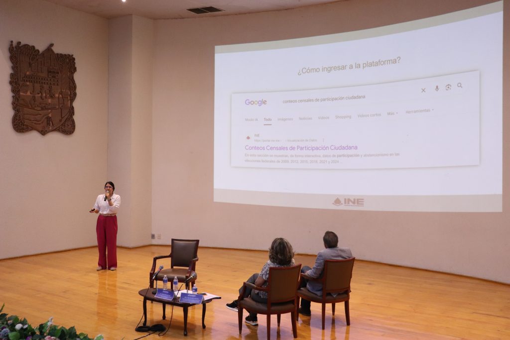 tres personas en un escenario de madera con una pantalla al frente