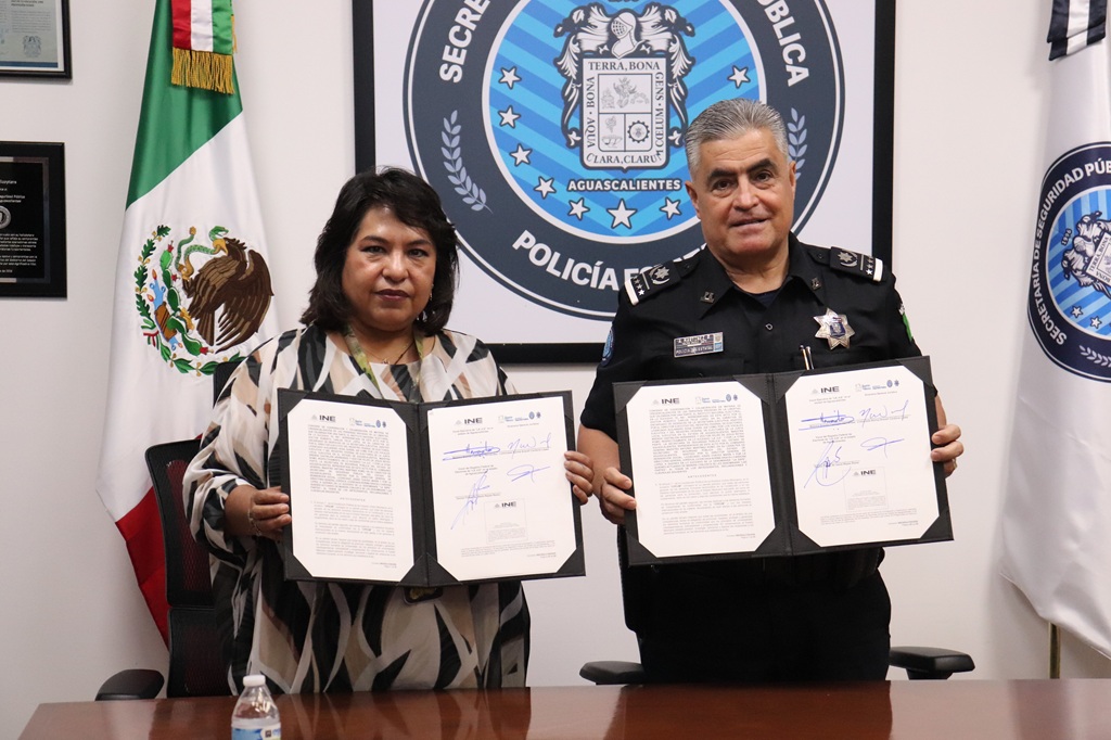 una mujer y un hombre con vestimenta de policía, ambos sostienen un documento