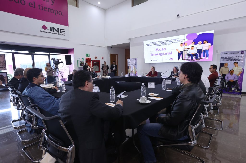 Personas en reunión en torno a una mesa cuadrada en un evento de la Unidad de Género y no discriminación