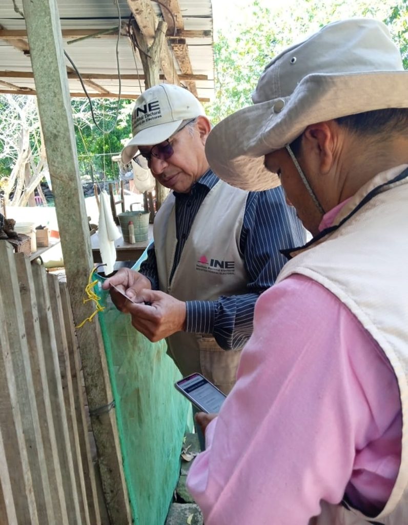 dos hombres de pie con gorras frente a una reja de madera